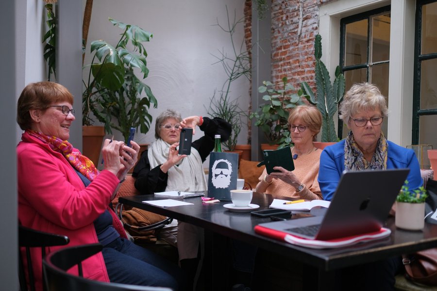 Deelnemers fotograferen met hun telefoon aan tafel tijdens een workshop