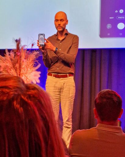 Maarten van Apeldoorn laat op het podium de camera-app van de telefoon zien