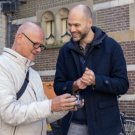 Deelnemer en docent lachen tijdens de drone-workshop, de controller in handen